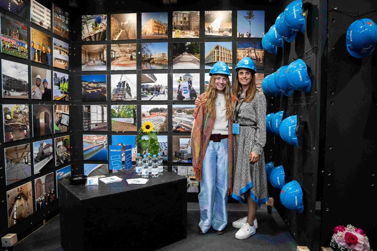 dve devojke sa plavim šlemovima na glavi stoje u prostoriji gde ima puno okačenih na zid plavih šlemova i fotografija
