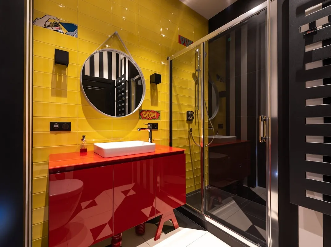 žuto crveni enterijer kupatila, i staklena tuš kabina